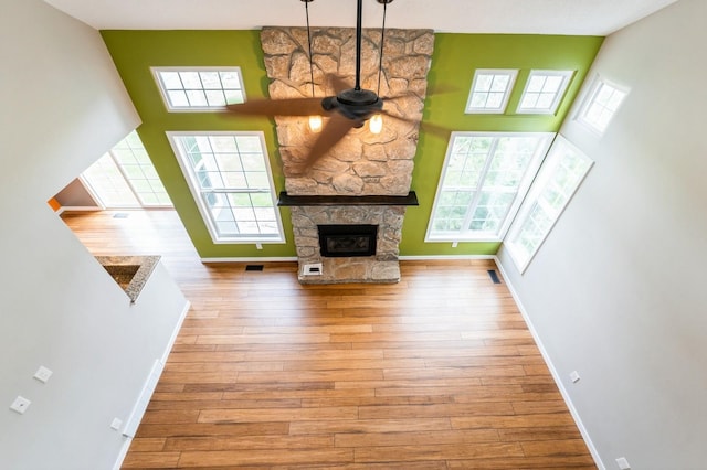 2405 81st Cir, Urbandale, IA 50322 - unfurnished living room featuring a towering ceiling, hardwood / wood-style floors, a fireplace, and a ceiling fan