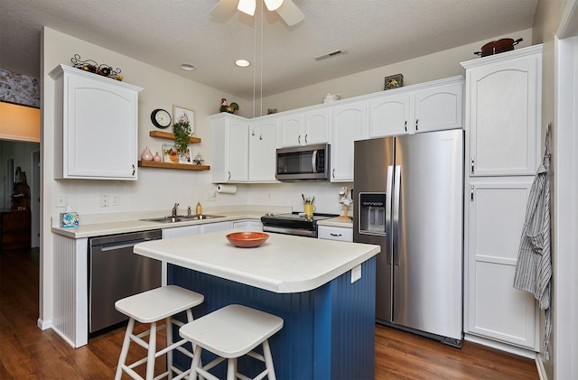280 S 79th St Unit 1302, West Des Moines, IA 50266 - kitchen featuring appliances with stainless steel finishes, dark wood-style flooring, white cabinetry, a sink, and a breakfast bar area
