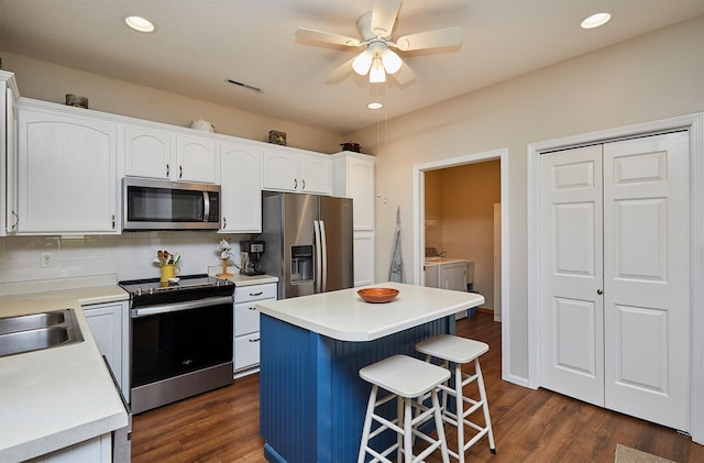 280 S 79th St Unit 1302, West Des Moines, IA 50266 - kitchen featuring appliances with stainless steel finishes, washing machine and clothes dryer, a ceiling fan, a breakfast bar area, and white cabinets