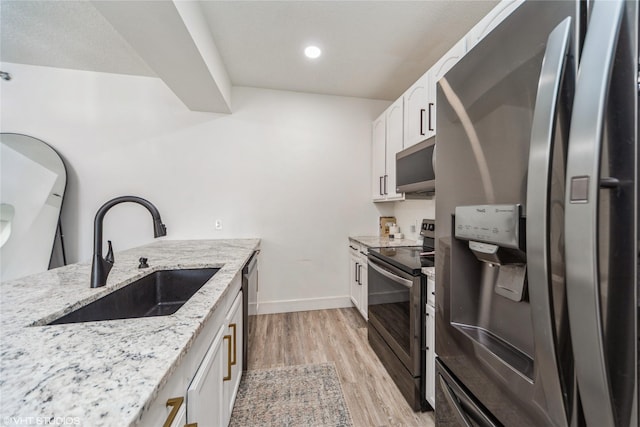 8601 Westown Pkwy Unit 21207, West Des Moines, IA 50266 - kitchen with appliances with stainless steel finishes, a sink, light stone counters, white cabinets, and light wood finished floors