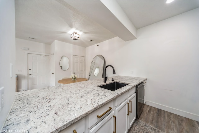 8601 Westown Pkwy Unit 21207, West Des Moines, IA 50266 - kitchen featuring a sink, dishwasher, dark wood-style flooring, light stone countertops, and a peninsula