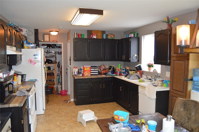 104 Walnut Dr NW, Bondurant, IA 50035 - kitchen featuring under cabinet range hood, white range, a sink, light countertops, and dark cabinetry