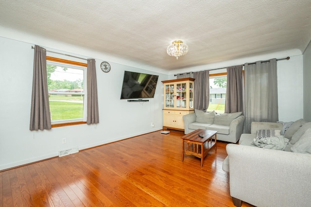 7409 Palm Dr, Urbandale, IA 50322 - living area with light wood finished floors, baseboards, a textured ceiling, and a chandelier