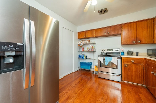 7409 Palm Dr, Urbandale, IA 50322 - kitchen with stainless steel appliances, wood finished floors, light countertops, and brown cabinets