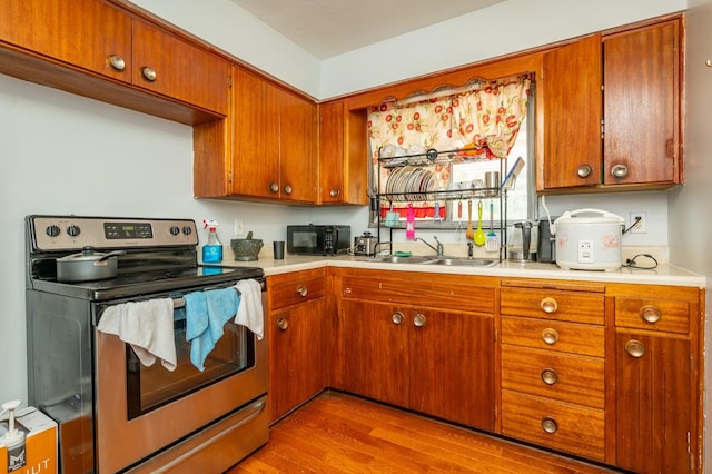 7409 Palm Dr, Urbandale, IA 50322 - kitchen with stainless steel electric range, black microwave, wood finished floors, light countertops, and brown cabinets