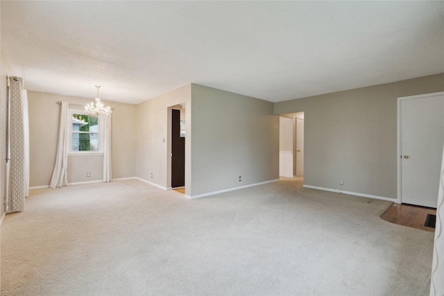 2901 E 40th Ct, Des Moines, IA 50317 - empty room featuring a chandelier, baseboards, and light carpet