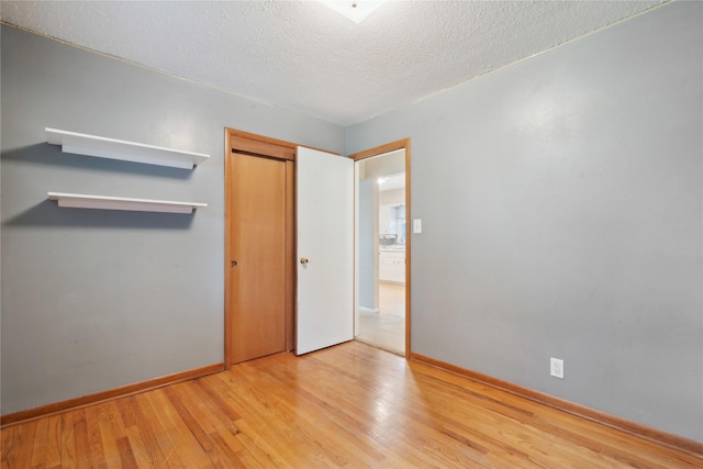 2901 E 40th Ct, Des Moines, IA 50317 - unfurnished bedroom featuring wood finished floors, a closet, baseboards, and a textured ceiling