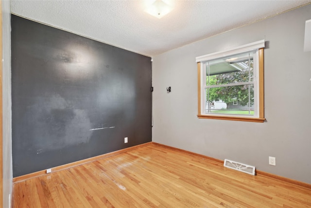 2901 E 40th Ct, Des Moines, IA 50317 - spare room with wood finished floors, a textured ceiling, and baseboards