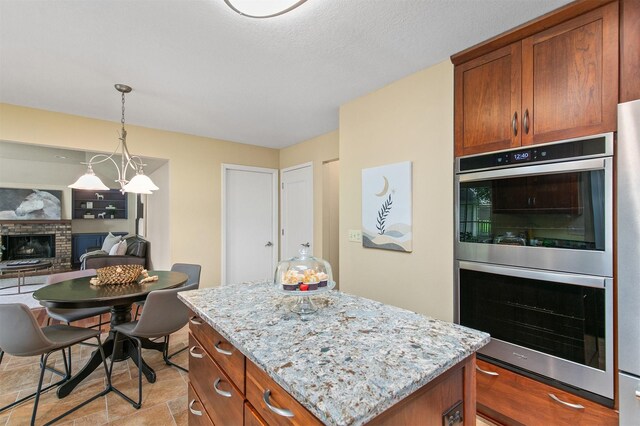 3510 Wolcott Ave, Des Moines, IA 50321 - kitchen with stainless steel double oven, a brick fireplace, light stone countertops, and a center island