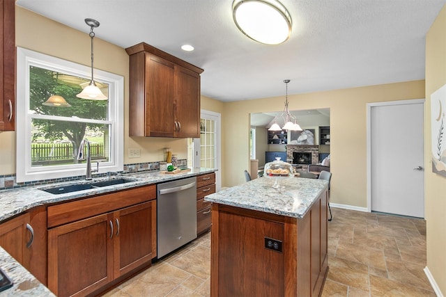 3510 Wolcott Ave, Des Moines, IA 50321 - kitchen with dishwasher, a sink, light stone counters, a fireplace, and decorative light fixtures