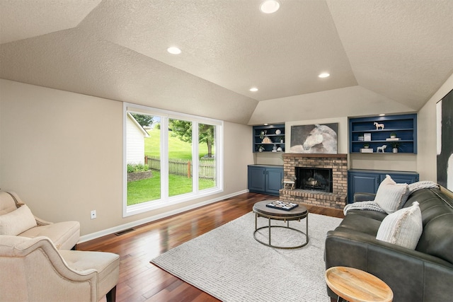 3510 Wolcott Ave, Des Moines, IA 50321 - living room with a textured ceiling, lofted ceiling, dark wood-style floors, baseboards, and built in shelves