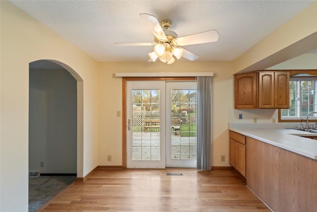 1495 Rio Valley Dr, Clive, IA 50325 - kitchen with light wood finished floors, ceiling fan, light countertops, arched walkways, and a textured ceiling