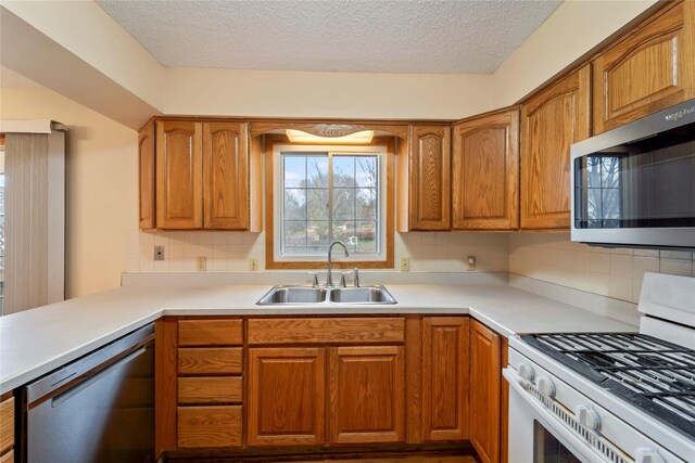 1495 Rio Valley Dr, Clive, IA 50325 - kitchen with appliances with stainless steel finishes, a sink, a textured ceiling, decorative backsplash, and light countertops