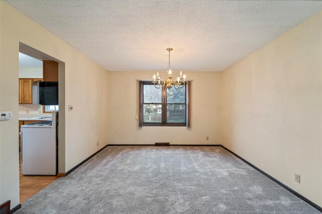 1495 Rio Valley Dr, Clive, IA 50325 - unfurnished room with a chandelier, light carpet, baseboards, and a textured ceiling
