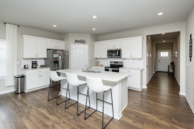 6828 NW 106th St, Johnston, IA 50131 - kitchen featuring appliances with stainless steel finishes, a kitchen bar, a center island with sink, dark wood finished floors, and recessed lighting