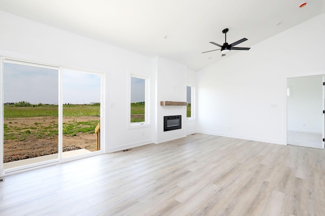 2412 NE 6th St, Grimes, IA 50111 - unfurnished living room featuring light wood-type flooring, a ceiling fan, a glass covered fireplace, high vaulted ceiling, and baseboards