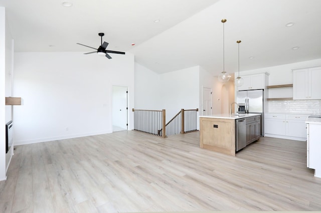 2412 NE 6th St, Grimes, IA 50111 - kitchen featuring open floor plan, stainless steel appliances, ceiling fan, light countertops, and high vaulted ceiling