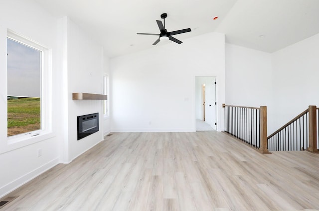 2412 NE 6th St, Grimes, IA 50111 - unfurnished living room with a glass covered fireplace, wood finished floors, vaulted ceiling, ceiling fan, and baseboards