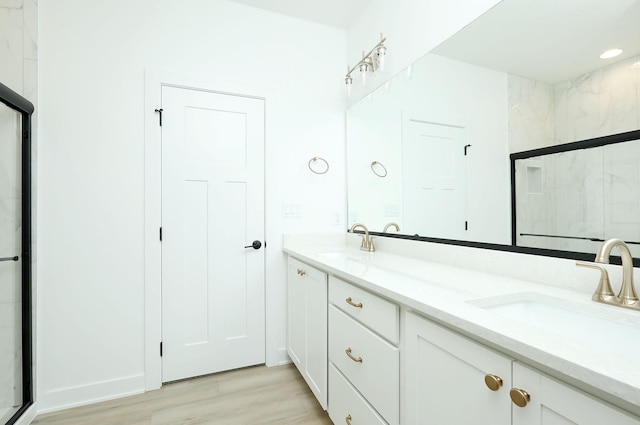 2412 NE 6th St, Grimes, IA 50111 - bathroom featuring double vanity, a shower stall, and wood finished floors