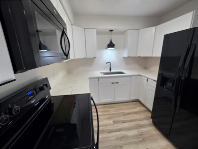 108 E Philip St, Des Moines, IA 50315 - kitchen with black appliances, a sink, white cabinetry, and light wood-style floors