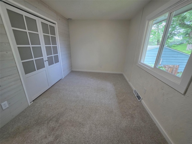 108 E Philip St, Des Moines, IA 50315 - spare room with carpet floors, baseboards, french doors, and wood walls