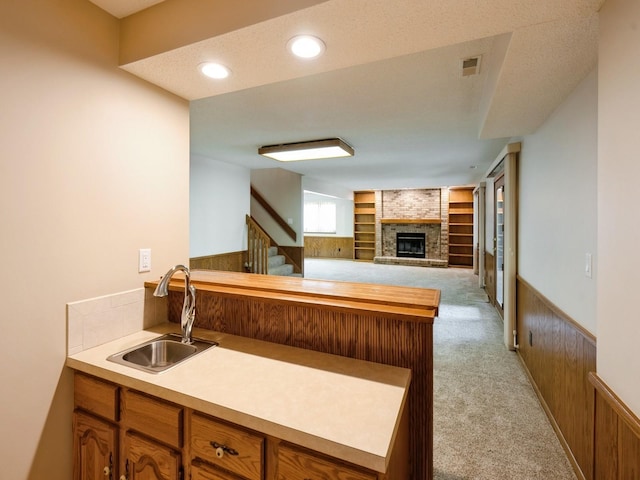 10823 Elmcrest Dr, Clive, IA 50325 - kitchen featuring a sink, light carpet, a brick fireplace, and brown cabinets