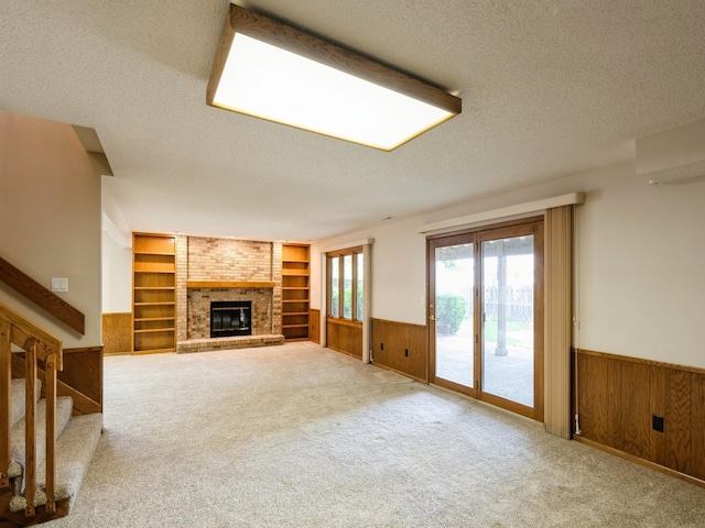 10823 Elmcrest Dr, Clive, IA 50325 - unfurnished living room featuring wainscoting, a textured ceiling, built in features, wooden walls, and a brick fireplace