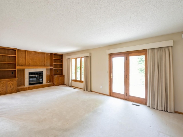 10823 Elmcrest Dr, Clive, IA 50325 - unfurnished living room featuring a textured ceiling, a tiled fireplace, baseboards, and light colored carpet
