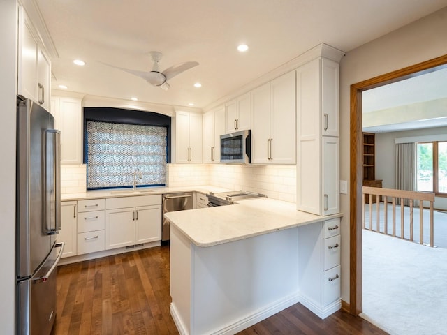 10823 Elmcrest Dr, Clive, IA 50325 - kitchen with stainless steel appliances, a peninsula, dark wood-style flooring, white cabinetry, and recessed lighting