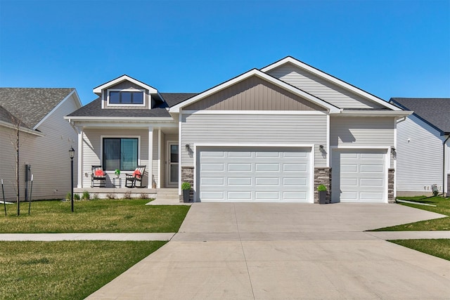6744 NE 12th Ct, Des Moines, IA 50313 - view of front of home with a porch, an attached garage, a front lawn, and stone siding