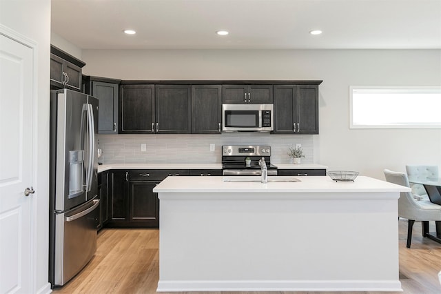 6744 NE 12th Ct, Des Moines, IA 50313 - kitchen featuring appliances with stainless steel finishes, backsplash, light wood-type flooring, light countertops, and recessed lighting