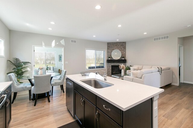 6744 NE 12th Ct, Des Moines, IA 50313 - kitchen with a sink, stainless steel dishwasher, light countertops, light wood-style floors, and recessed lighting