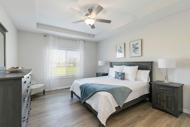 6744 NE 12th Ct, Des Moines, IA 50313 - bedroom featuring a raised ceiling, light wood-type flooring, baseboards, and a ceiling fan