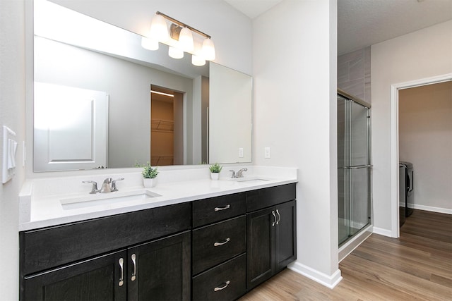 6744 NE 12th Ct, Des Moines, IA 50313 - bathroom with a walk in closet, a stall shower, double vanity, and wood finished floors