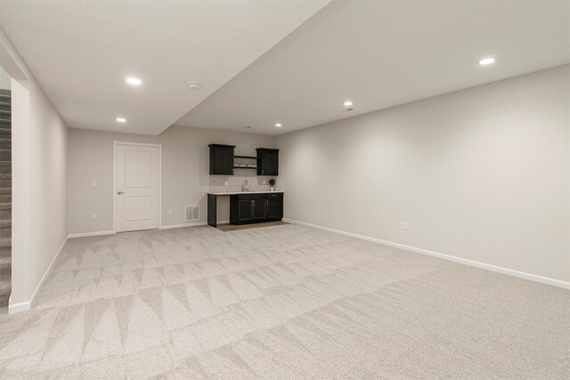 6744 NE 12th Ct, Des Moines, IA 50313 - unfurnished living room with bar with sink, stairs, recessed lighting, baseboards, and light carpet