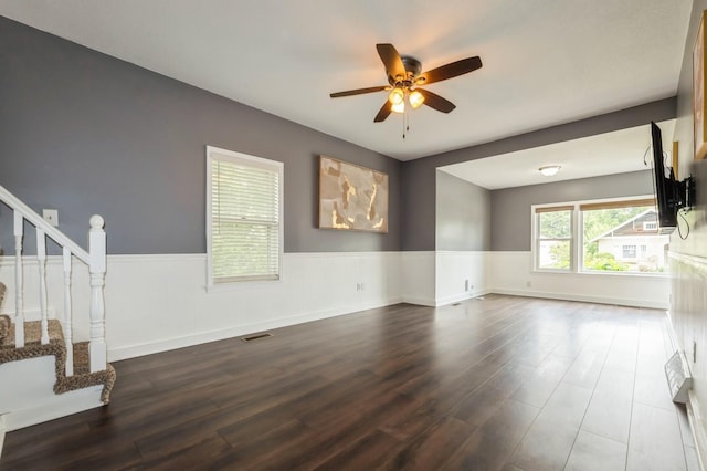600 SE 2nd St, Grimes, IA 50111 - unfurnished living room featuring ceiling fan, dark wood-style floors, stairs, and a wainscoted wall