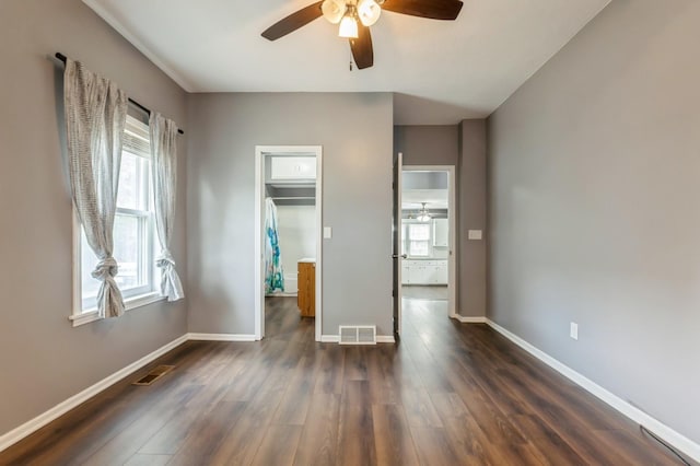 600 SE 2nd St, Grimes, IA 50111 - unfurnished bedroom featuring multiple windows, a spacious closet, dark wood-type flooring, and baseboards