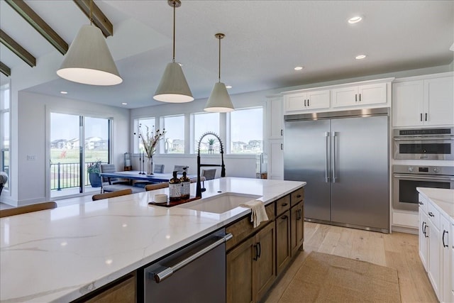3736 NW 183rd St, Clive, IA 50325 - kitchen featuring appliances with stainless steel finishes, hanging light fixtures, light stone counters, light wood-type flooring, and white cabinetry
