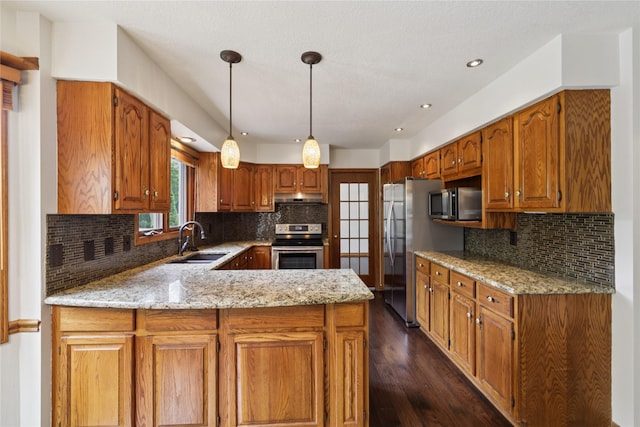 313 29th St, West Des Moines, IA 50265 - kitchen featuring appliances with stainless steel finishes, a sink, under cabinet range hood, a peninsula, and dark wood finished floors