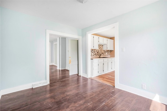 1127 10th St, Des Moines, IA 50314 - unfurnished room with wood finished floors, a sink, and baseboards