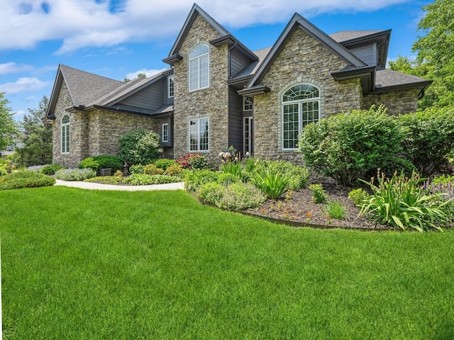 11576 NW Timberbrooke Ln, Grimes, IA 50111 - view of front of house with stone siding, a front yard, and a shingled roof