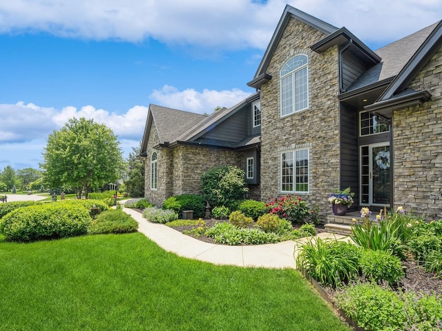 11576 NW Timberbrooke Ln, Grimes, IA 50111 - view of side of home with stone siding, a yard, and a shingled roof