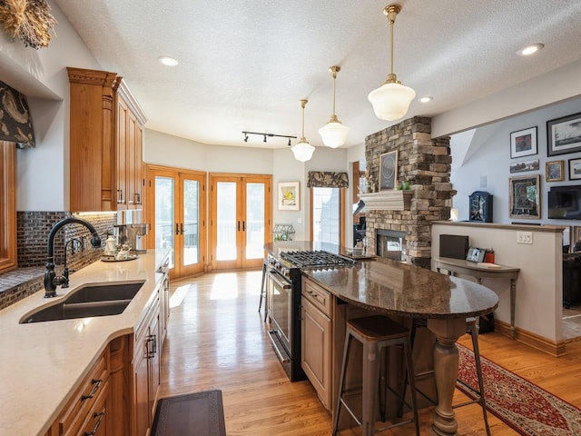 11576 NW Timberbrooke Ln, Grimes, IA 50111 - kitchen featuring a sink, stainless steel range, a kitchen island, french doors, and light wood-type flooring
