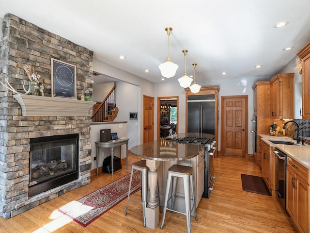 11576 NW Timberbrooke Ln, Grimes, IA 50111 - kitchen featuring appliances with stainless steel finishes, a sink, a center island, a breakfast bar area, and light wood-type flooring