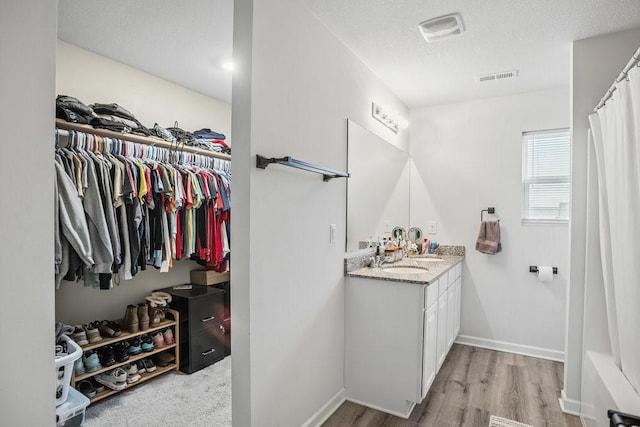 5400 Brook Landing Cir, Des Moines, IA 50317 - full bath featuring vanity, wood finished floors, a textured ceiling, a spacious closet, and baseboards