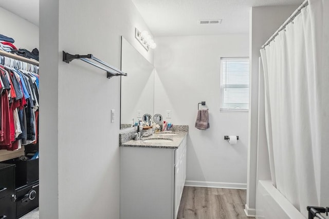 5400 Brook Landing Cir, Des Moines, IA 50317 - bathroom featuring vanity, wood finished floors, shower / bath combo with shower curtain, baseboards, and a spacious closet