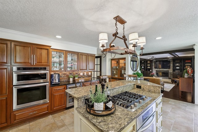 14091 Willow Dr, Clive, IA 50325 - kitchen with appliances with stainless steel finishes, a chandelier, brown cabinets, a textured ceiling, and crown molding