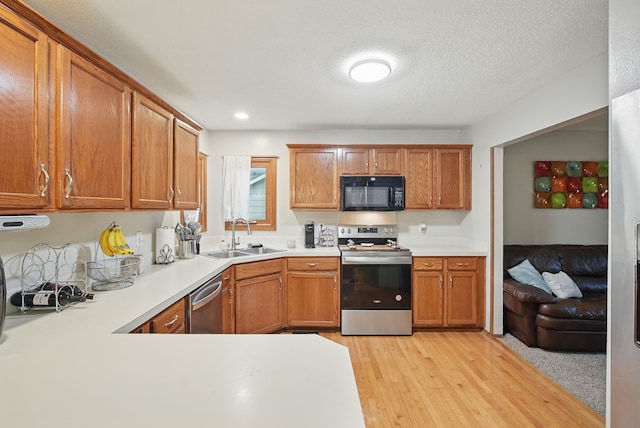 1290 S 4th St, Carlisle, IA 50047 - kitchen with appliances with stainless steel finishes, a sink, light countertops, light wood-style flooring, and brown cabinets
