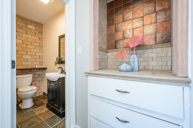 4005 Beaver Ave, Des Moines, IA 50310 - bathroom with stone finish flooring, vanity, toilet, and decorative backsplash