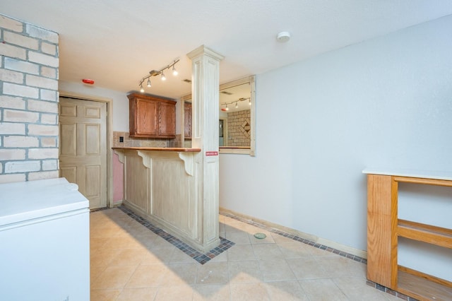 4005 Beaver Ave, Des Moines, IA 50310 - kitchen featuring rail lighting, light tile patterned flooring, a breakfast bar area, white fridge, and baseboards